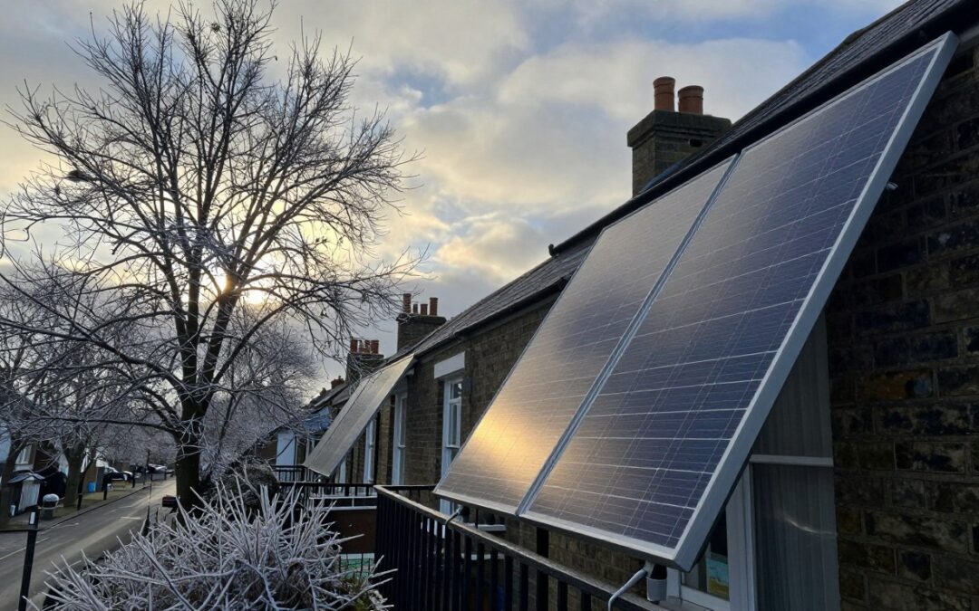 Plug-in solar panels on a UK terraced house balcony in winter, catching low sunlight through grey clouds